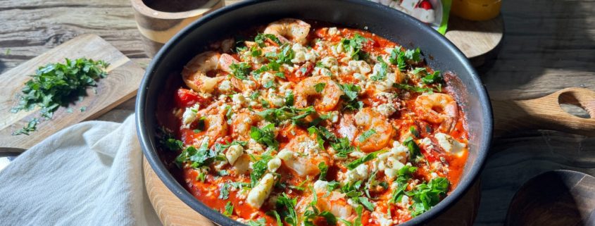 Creveți saganaki gătiți în sos de roșii și usturoi, cu telemea de vacă Delaco sfărâmată deasupra