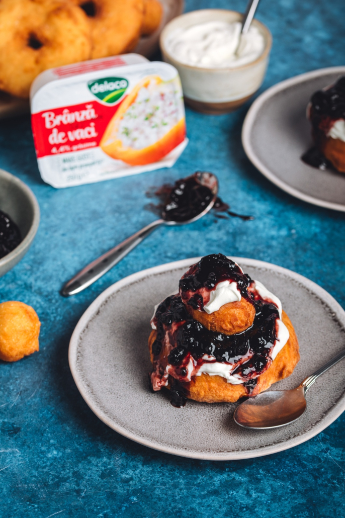 Porție de papanași prăjiți cu smântână și dulceață, desert românesc popular.