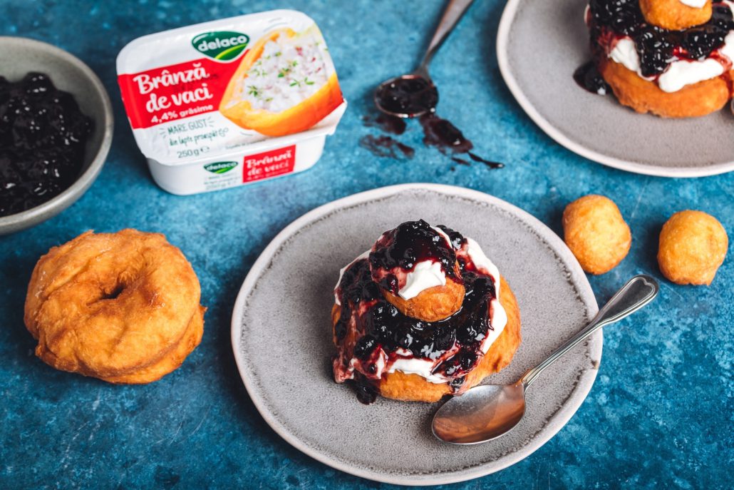 Papanași prăjiți tradiționali cu brânză de vaci Delaco, serviți cu smântână și dulceață.