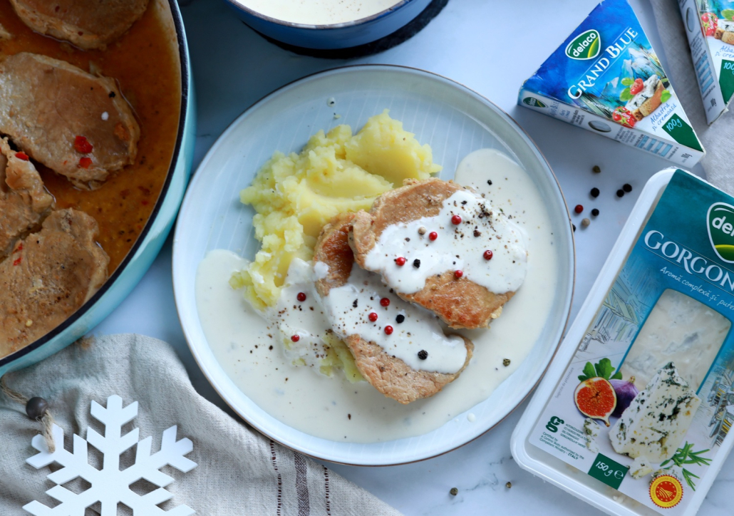 Friptură de porc la tigaie cu sos gorgonzola cremos și piure, servită în farfurie