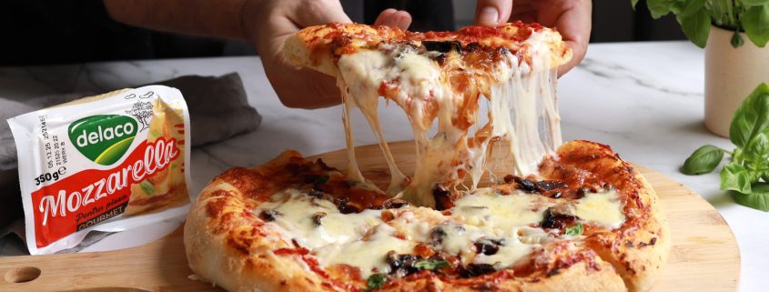 Felie de pizza cu ceapă caramelizată, bacon și mozzarella Delaco care se întinde