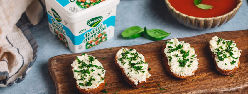 Bruschete cu Brânză Cremoasă Delaco și ierburi aromatice, servite alături de supă-cremă de roșii.