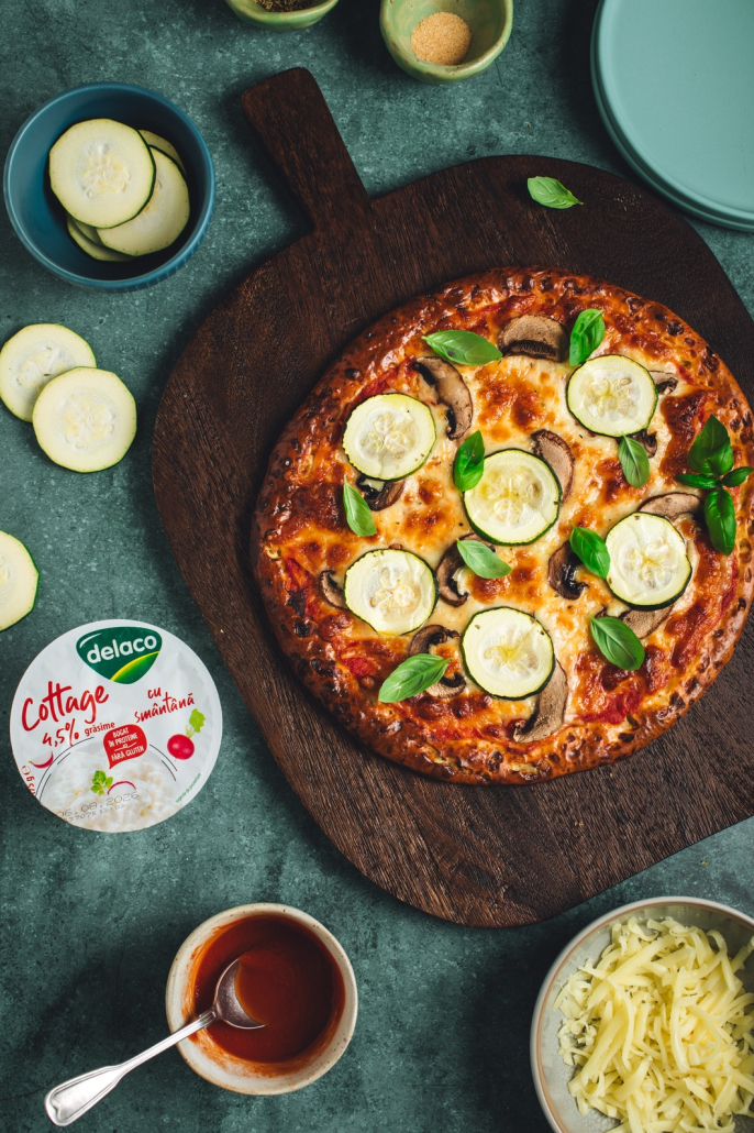 Pizza cu blat din Brânză Cottage Delaco, mozzarella topită, ciuperci și dovlecei, pregătită la cuptor.