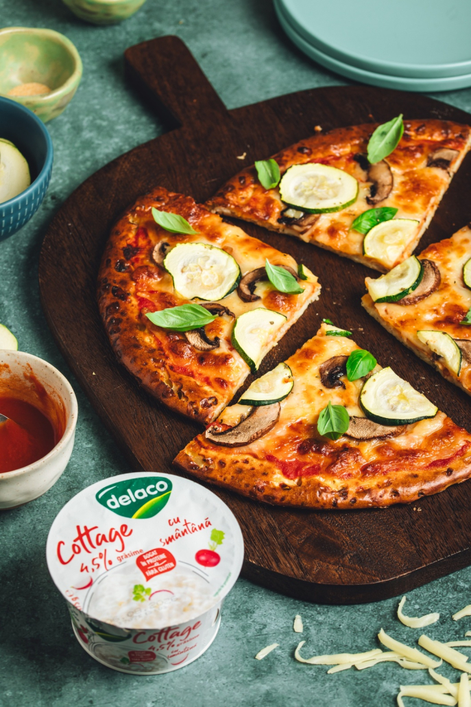 Pizza proteică cu blat din Brânză Cottage Delaco, acoperită cu mozzarella, ciuperci și dovlecei.