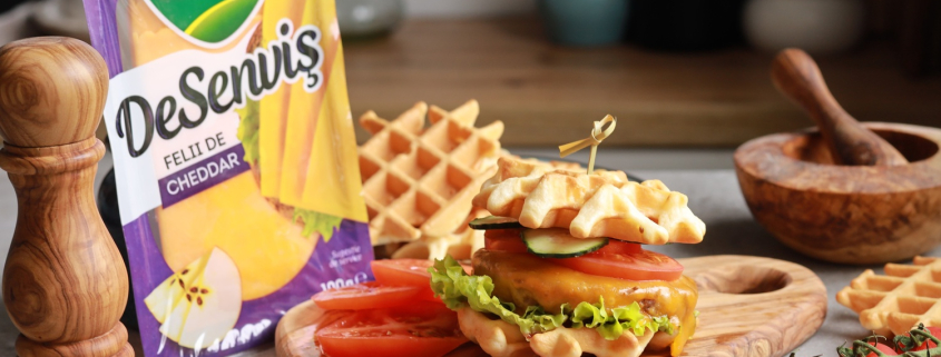 Waffle burger cu Cheddar DeSenviș, salată, roșii și castraveți